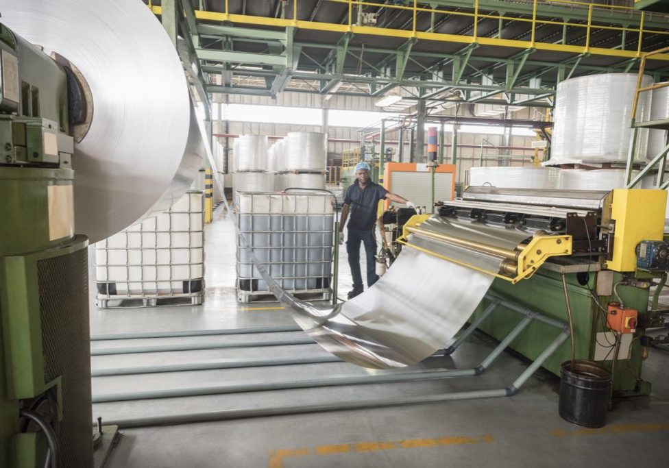 Man standing by large roll of aluminium in factory Roller Die Makes Parts from Many Metals